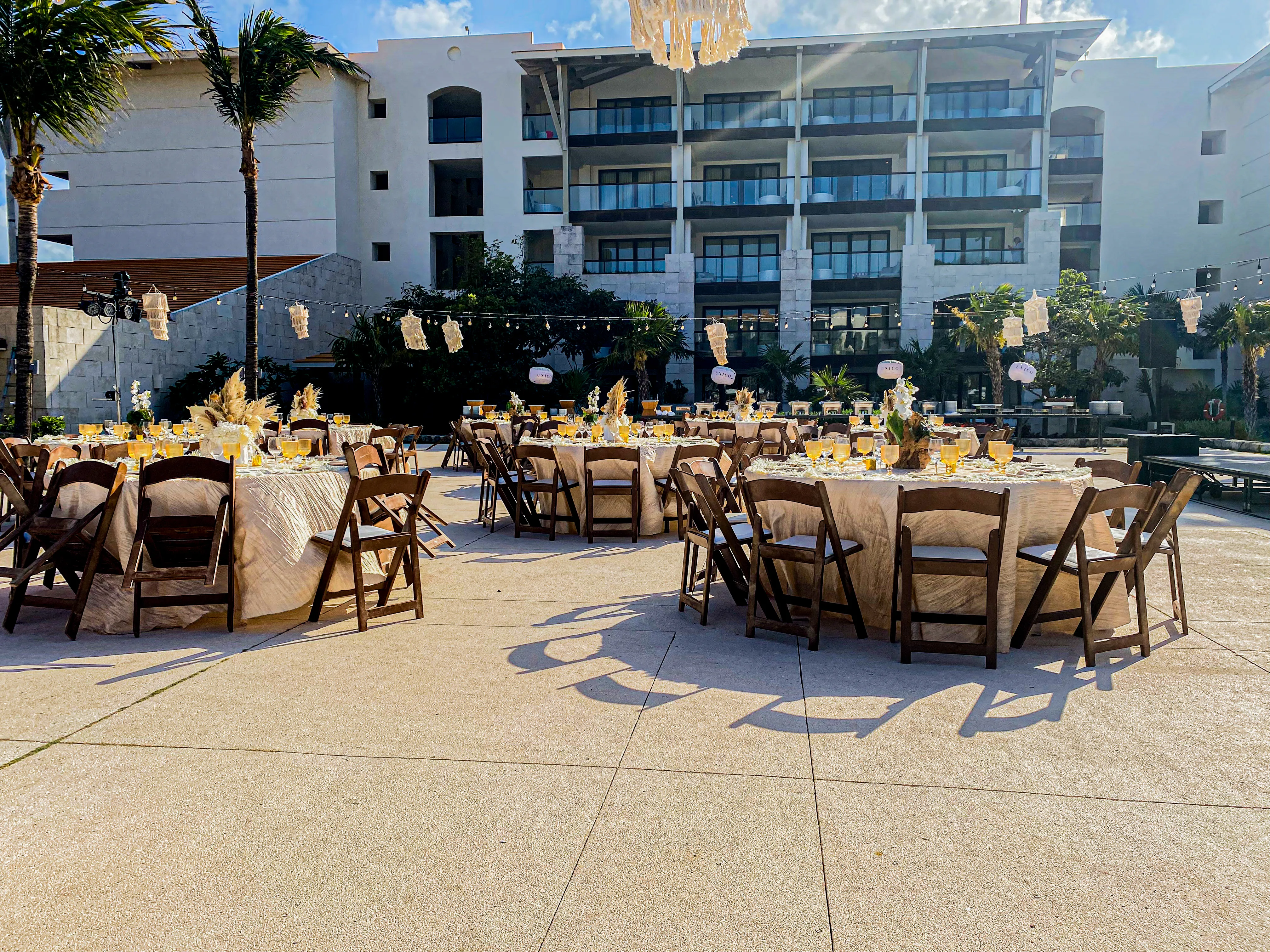 Boho dinner setup on Nayade Terrace with sandy beige linens, wooden chairs, amber goblets, and natural centerpieces.