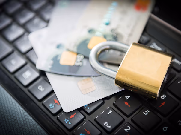 Two credit cards placed on a keyboard with a gold padlock resting on top, symbolizing online security.