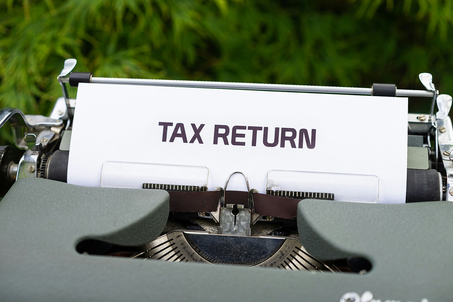 Close-up of a typewriter with a sheet of paper showing the words "TAX RETURN" in bold letters.
