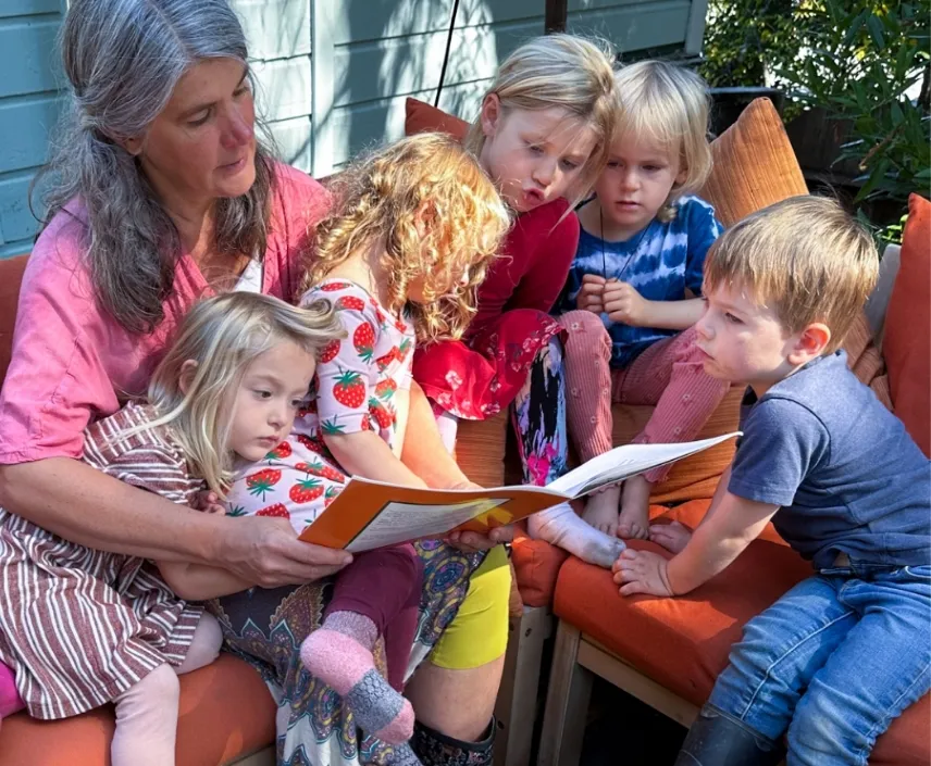 Illustration of a golden sun with a serene face surrounded by stars, symbolizing seasonal rhythm and storytelling.