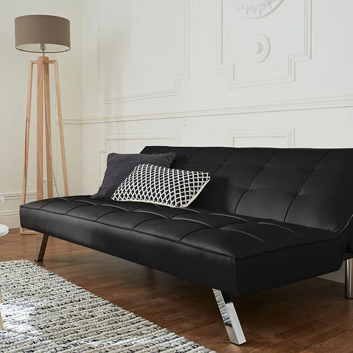 A black futon sofa sitting on top of a hard wood floor.