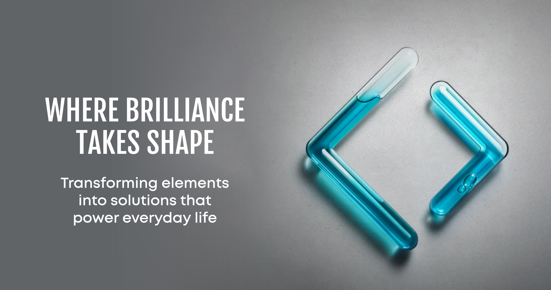 Two angled transparent test tubes filled with blue liquid forming a chevron shape on gray background.