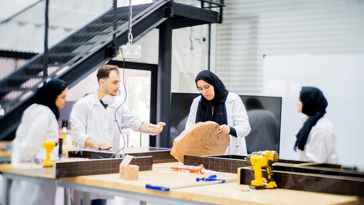 Four scientists in lab coats examining a large wood slice on a table with tools and equipment.