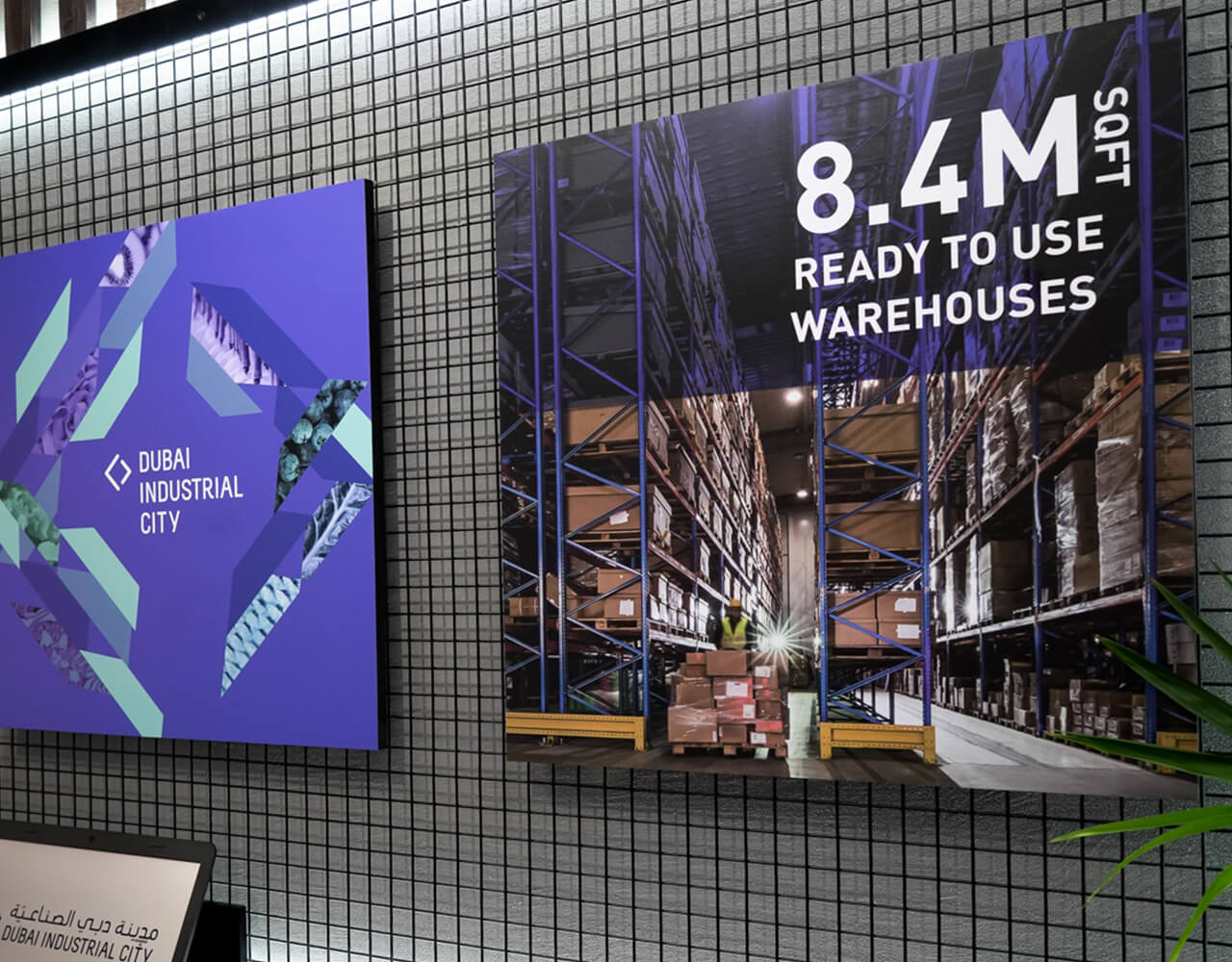 Wall posters showing Dubai Industrial City logo and image of large warehouse with 8.4M sq ft ready to use.