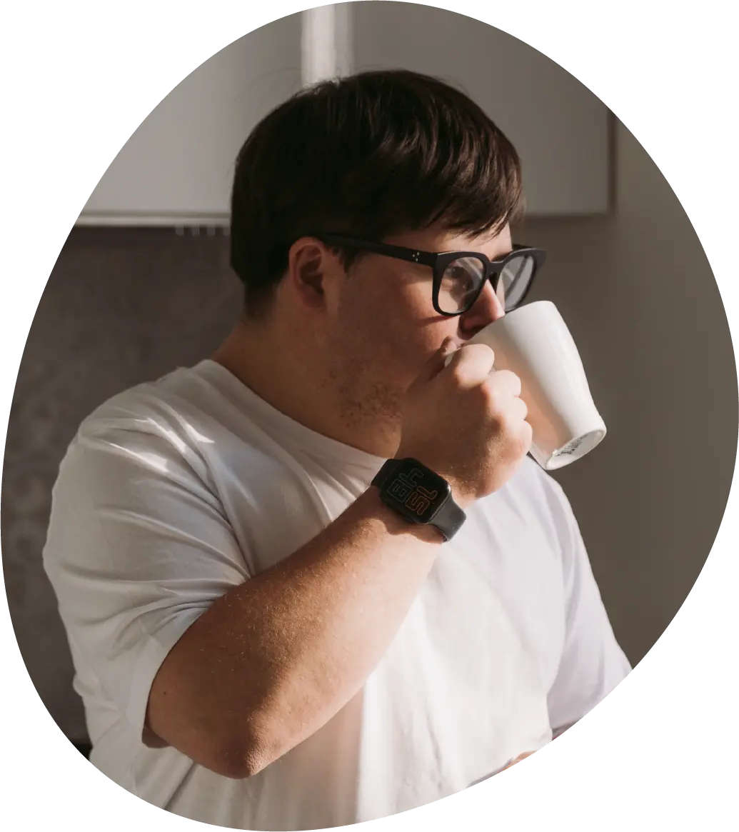A man in a white shirt drinking out of a cup.