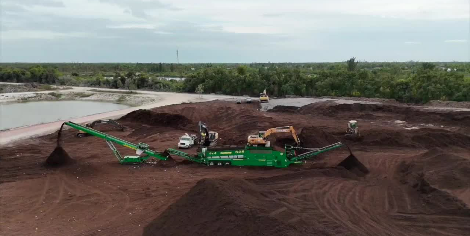 A large pile of dirt next to a body of water.