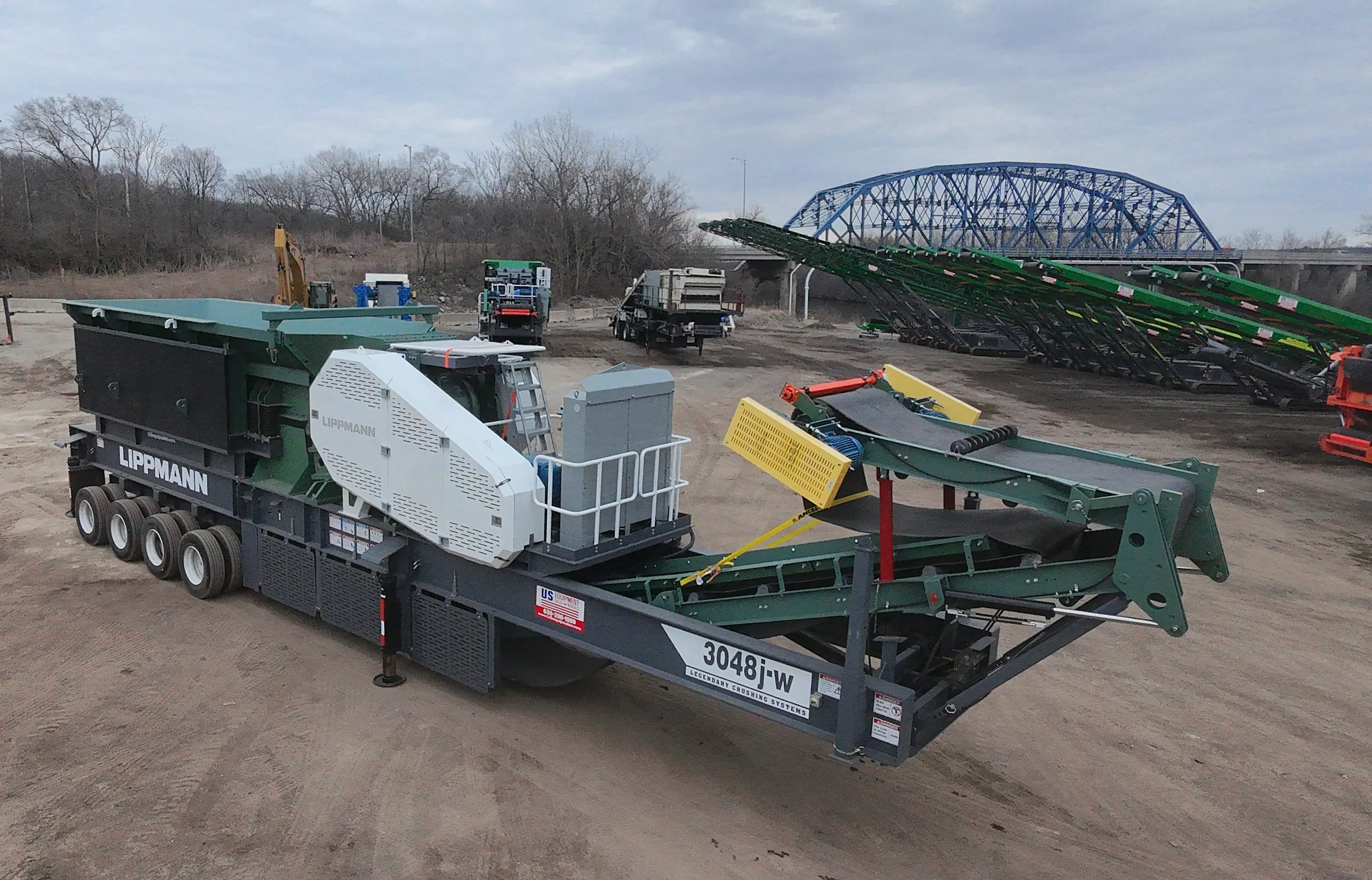 Lippmann 3048 portable jaw crusher system staged in a yard with conveyors and stackers in the background, ready for aggregate crushing operations.