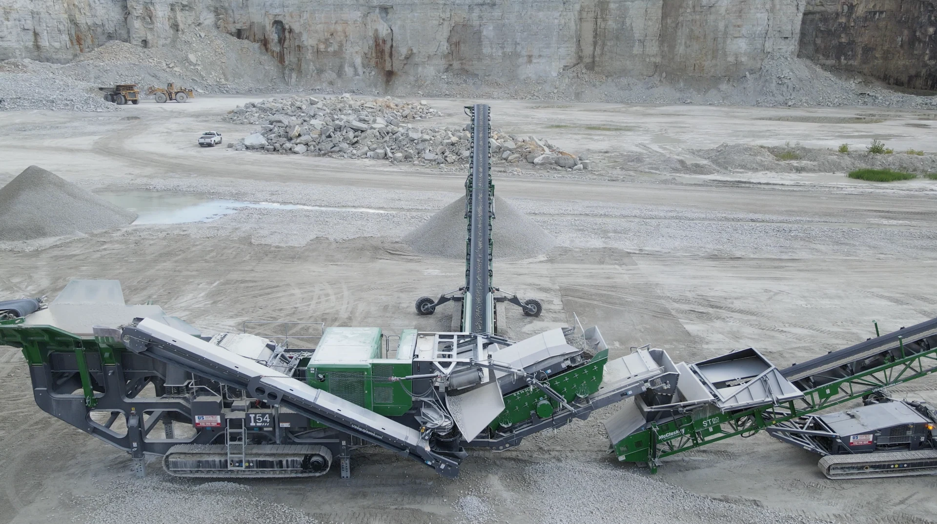 McCloskey I54 impact crusher feeding an ST80 stacker in a limestone quarry, producing material stockpiles during high-capacity crushing operations.