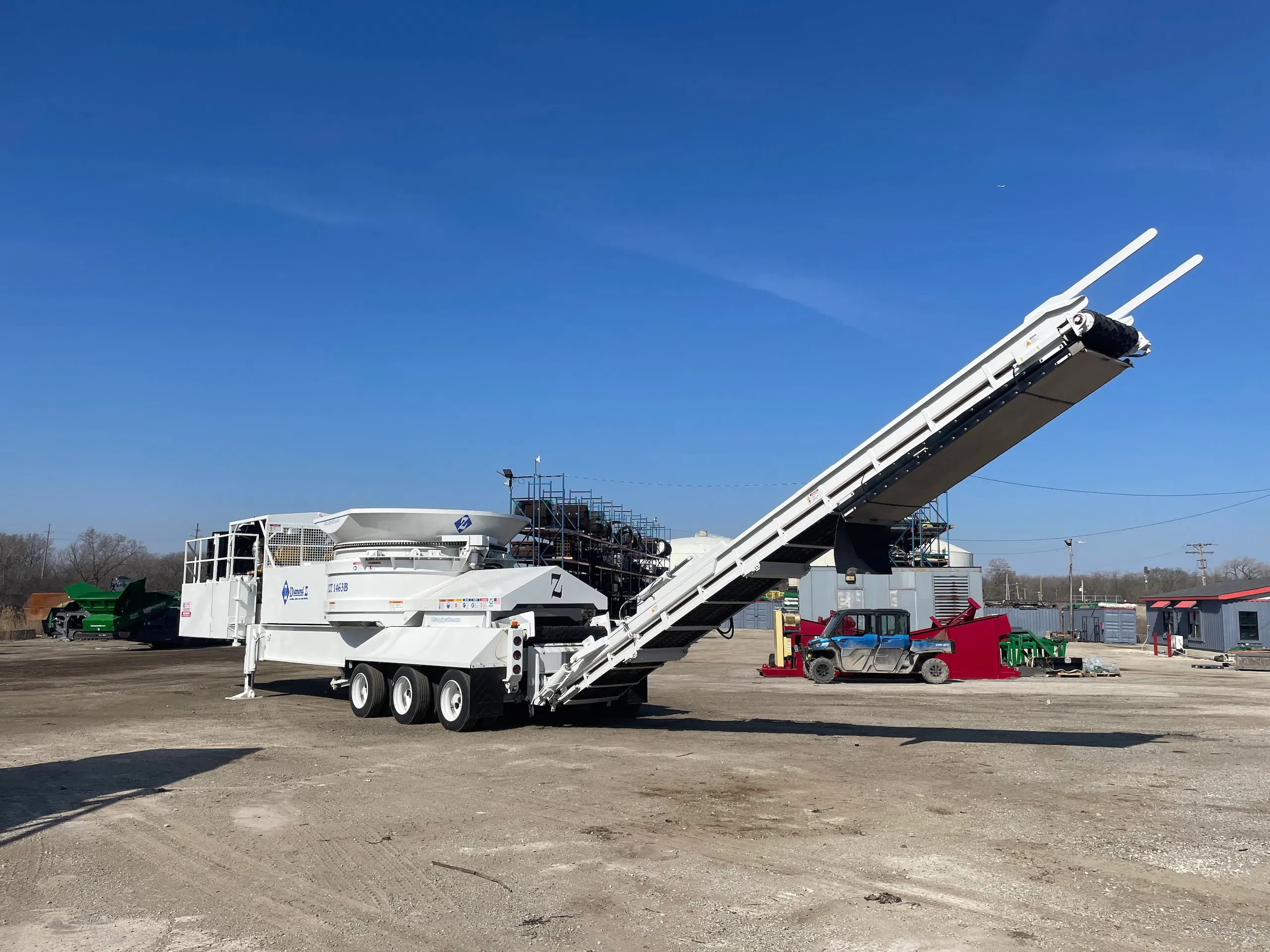 Diamond Z tub grinder with raised discharge conveyor, producing consistent ground material at an industrial processing site.