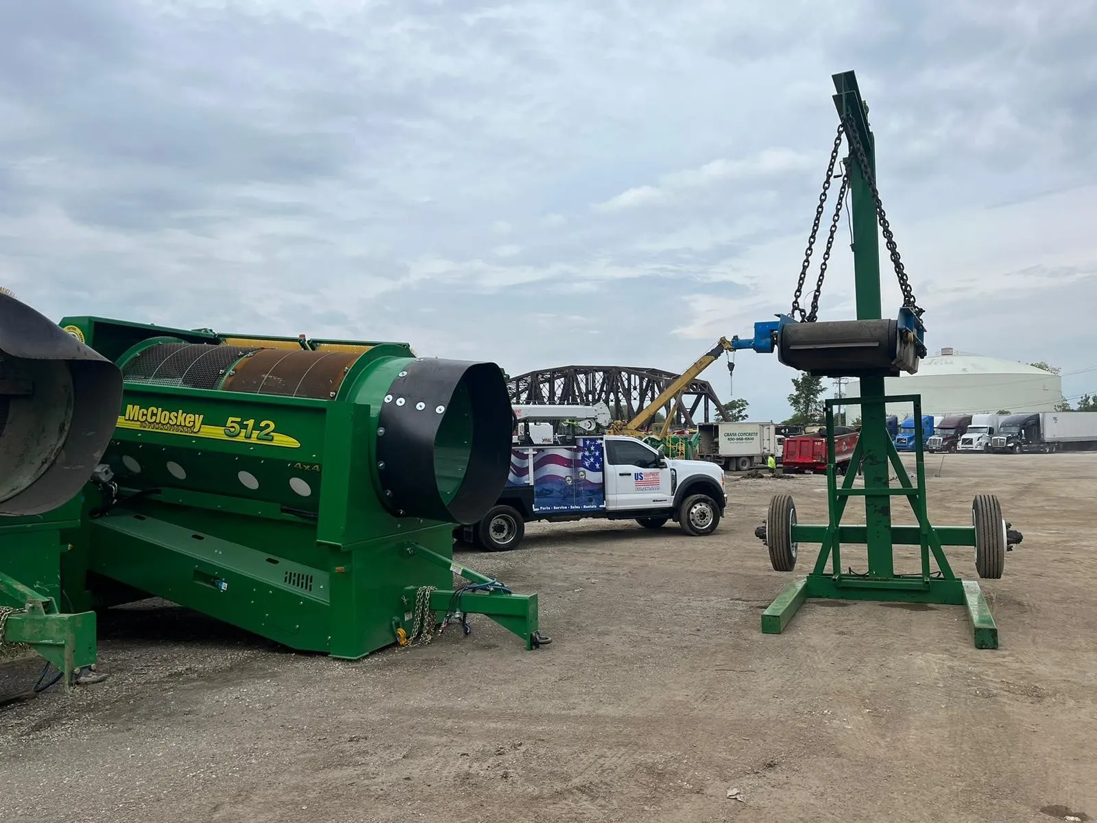 McCloskey 512 trommel screen positioned next to a conveyor support stand, used for material screening and separation.