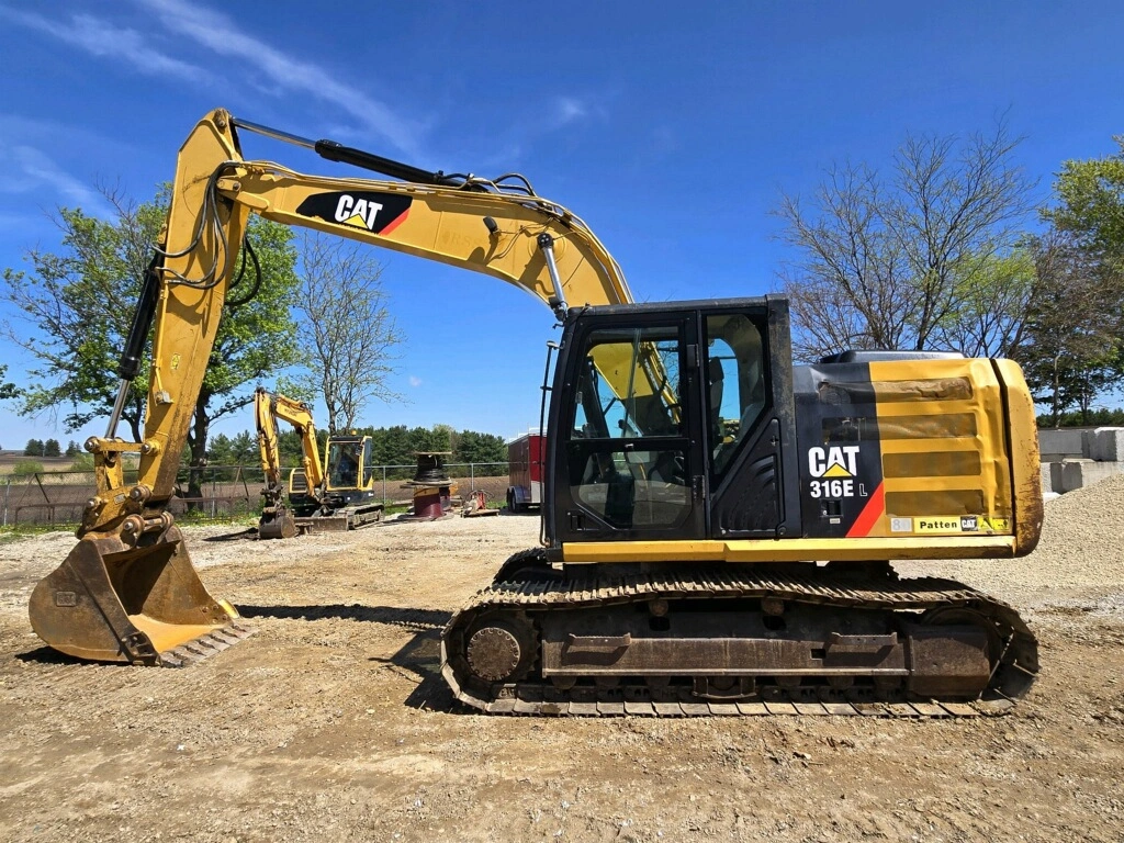 CAT 316 tracked excavator equipped with a bucket attachment, staged on a construction jobsite.