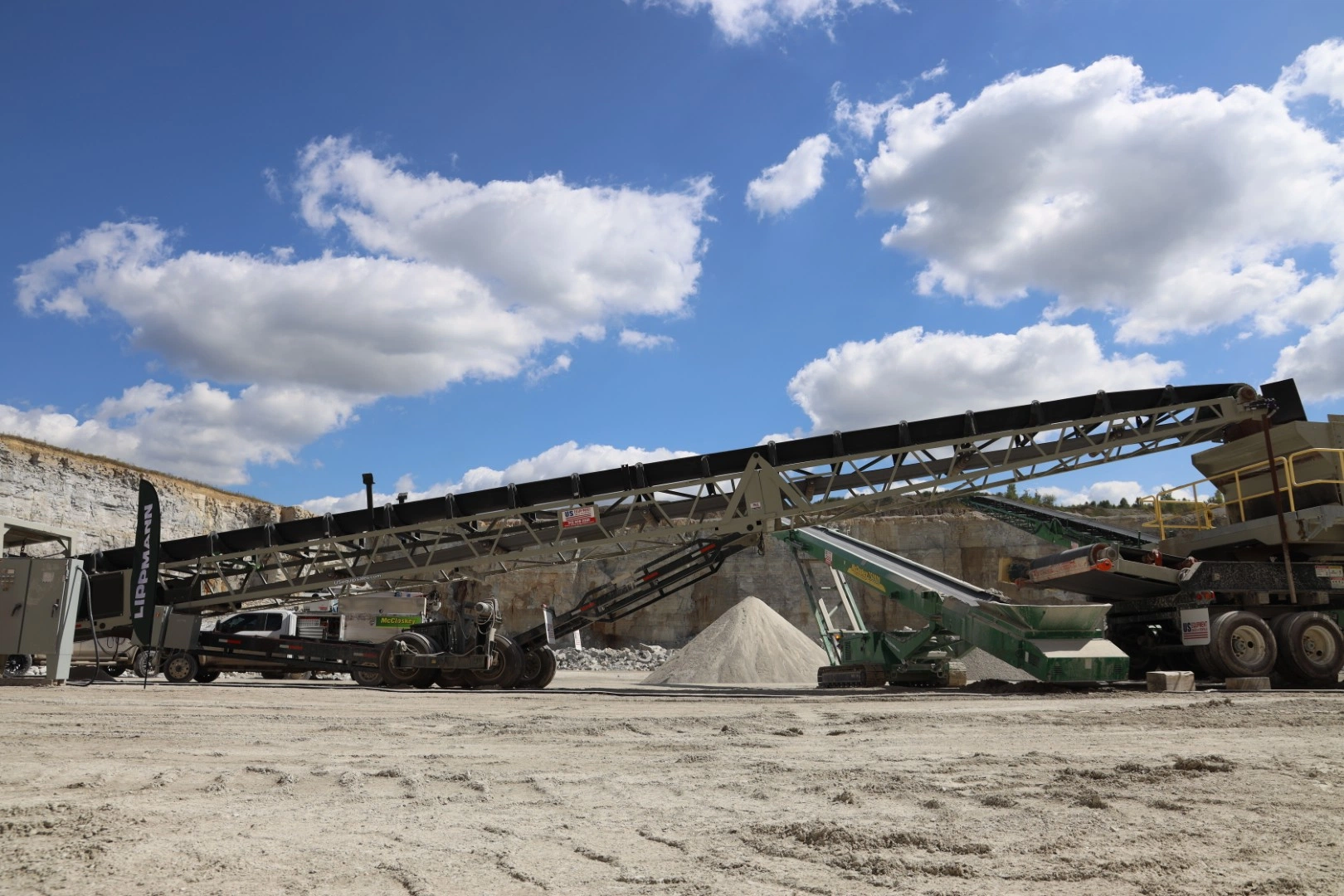 Extended conveyor line supporting a screening plant in a limestone quarry, moving material efficiently toward processing equipment.