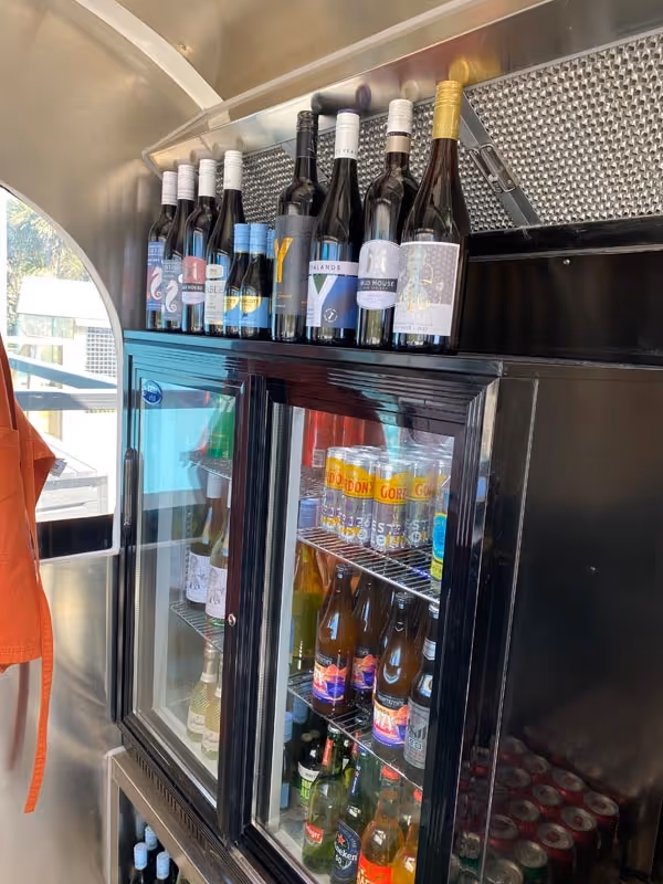 A cooler stocked with various drinks, including bottled beers, wines on top, and sodas inside. The scene suggests a relaxed, inviting atmosphere.