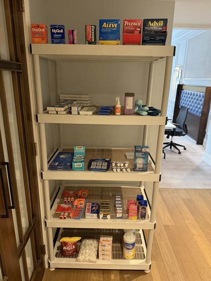 Supply station shelving stocked with toner, binders, and medicine