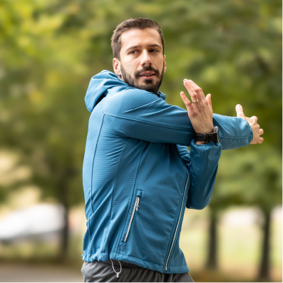A man in a blue jacket stretching his arms.