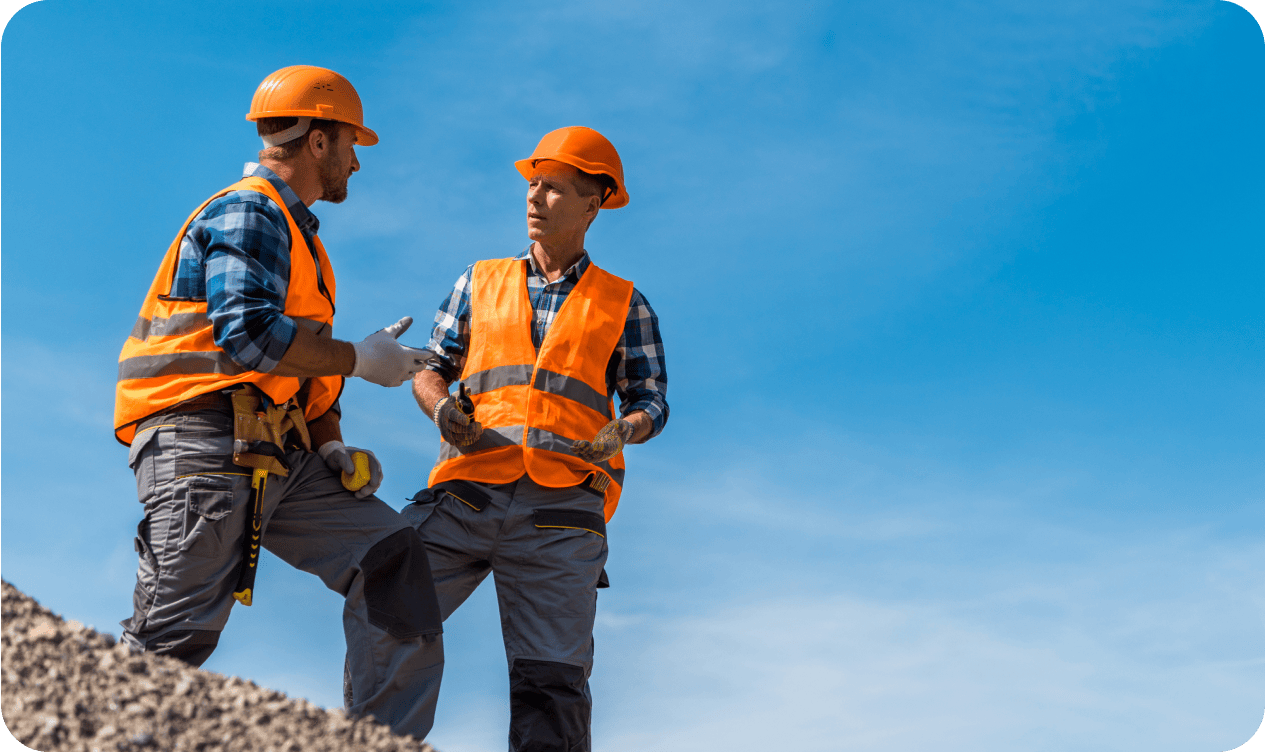 Construction workers discussing plans on site wearing safety gear