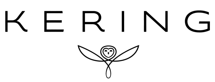 A man wearing a blue shirt and dark vest wearing sunglasses holds up a camera taking a photo.