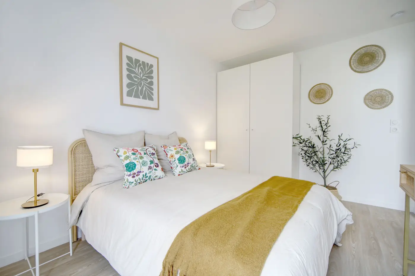 Chambre d'un appartement Mobicap avec lit double, tables de chevet et penderie