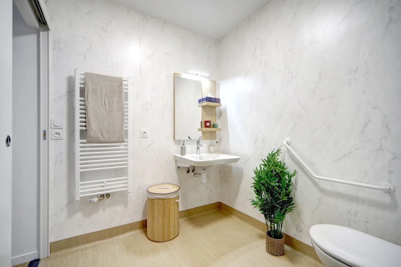 Salle d'eau accessible d'un appartement Mobicap avec lavabo dégagé et barre d'appui