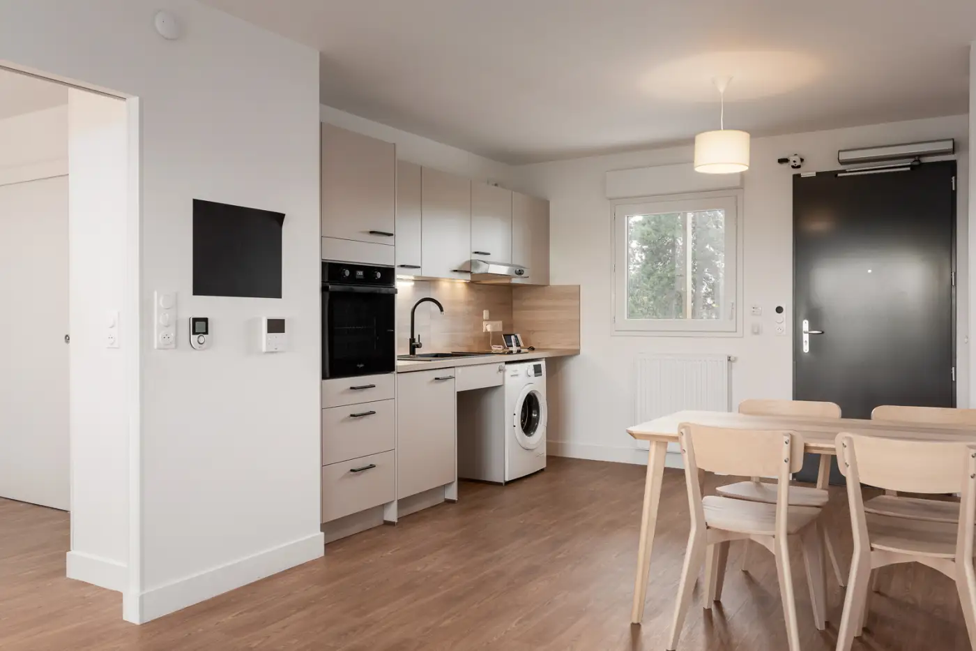 Pièce de vie avec cuisine équipée et coin repas, appartement Mobicap à Lisieux