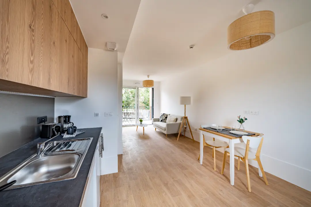 Séjour lumineux avec cuisine ouverte et accès au balcon, appartement Mobicap à Bourges