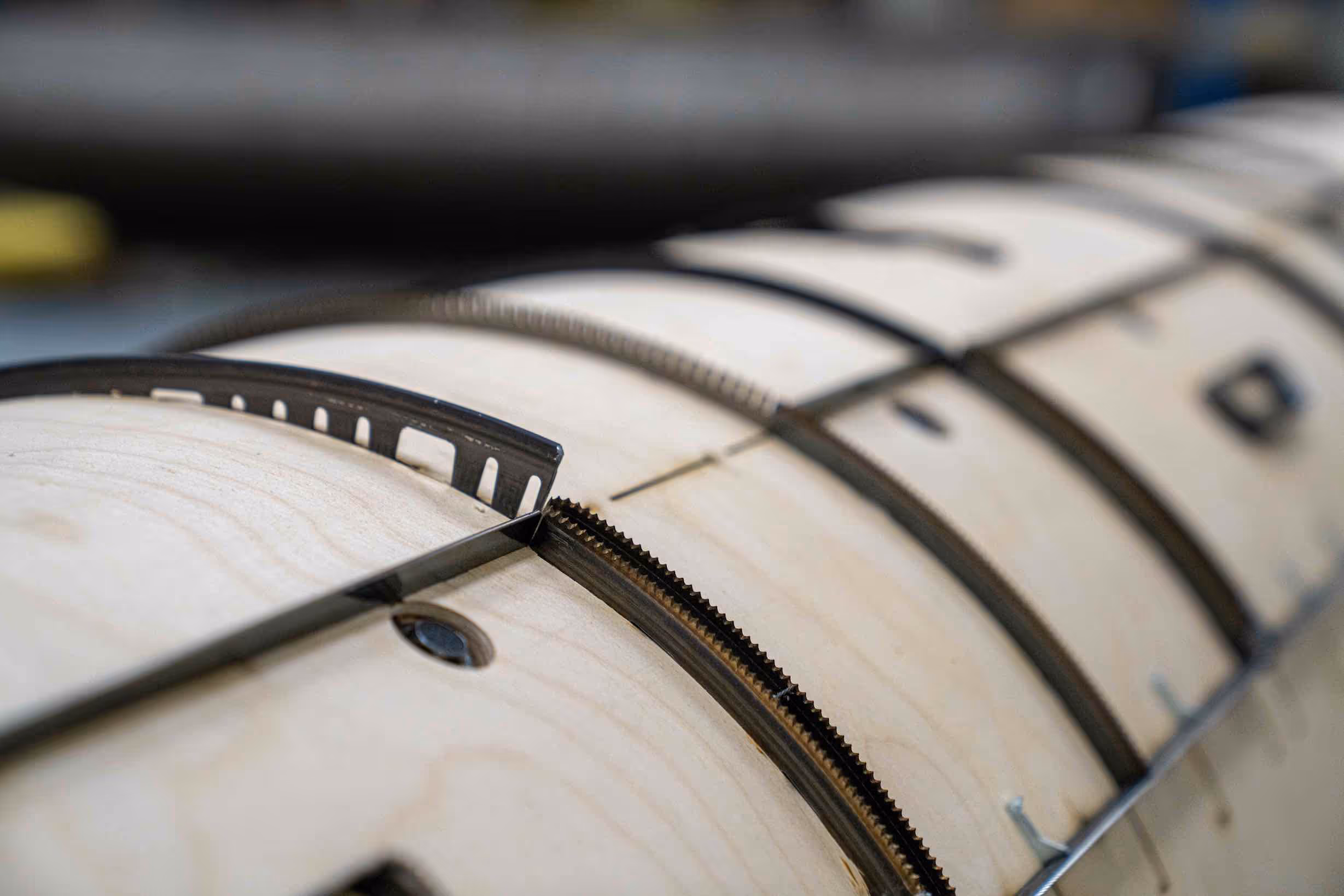 Close-up of a wooden core with metal bands and fasteners secured around it.