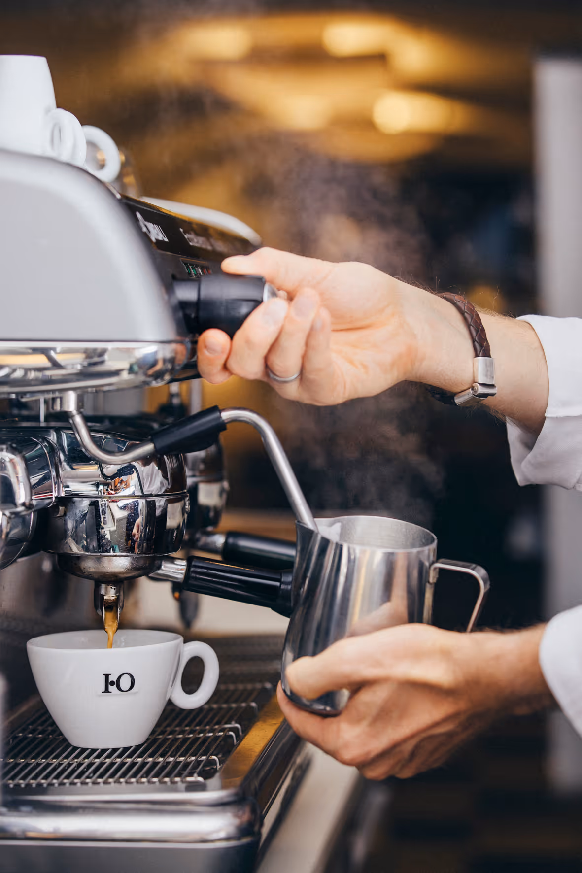 Barista schäumt Milch auf und macht Kaffee