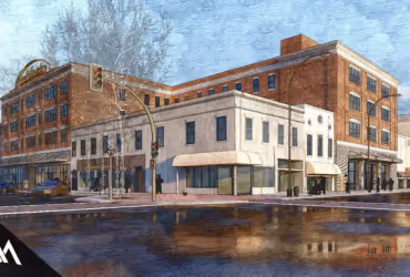 Street corner with red brick and white buildings reflected in a wet road under traffic lights on a cloudy day.