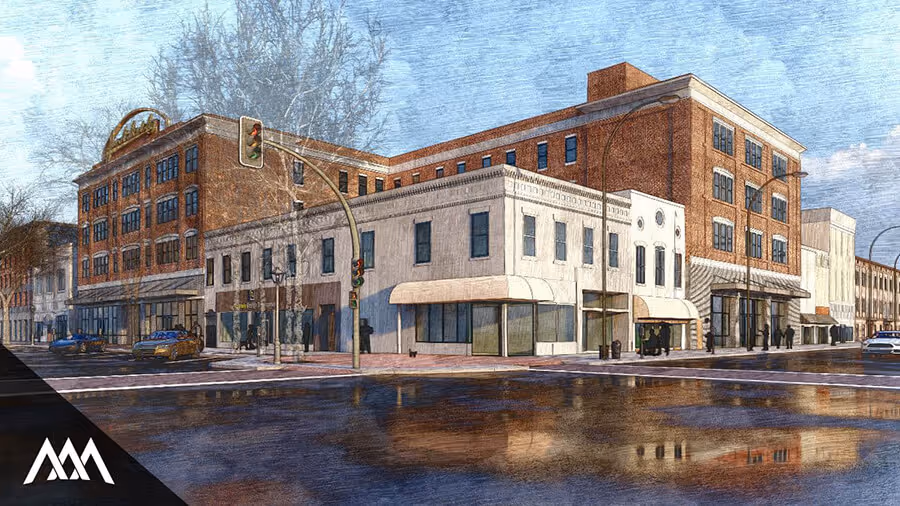 Street corner view of a multi-story brick and white storefront building with traffic lights and cars under a cloudy sky.