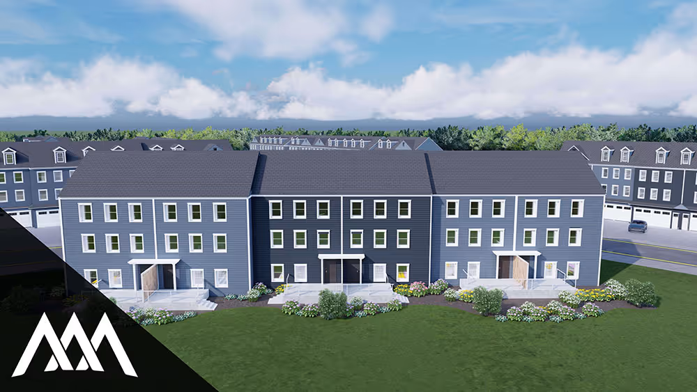 Modern row of three-story townhouse buildings with multiple windows, small front porches, and landscaped green lawn under a blue sky with clouds.