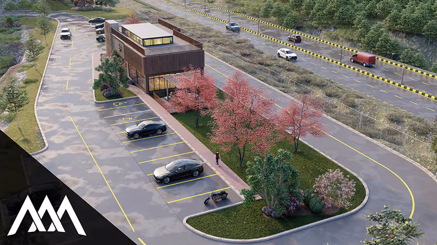Aerial view of a modern two-story building with large windows surrounded by a parking lot, flowered trees, and a curved driveway, with vehicles parked and driving on nearby roads.