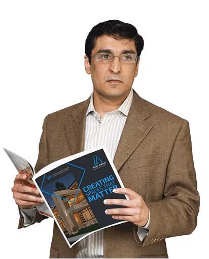 Man wearing glasses and a brown blazer holding and looking at a brochure titled 'Creating Spaces That Matter' with an image of a modern house.