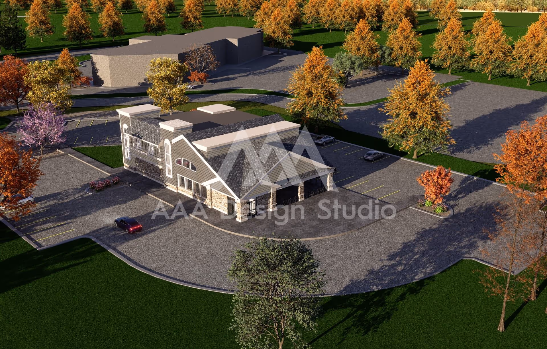 Aerial view of a modern two-story building with a stone and siding exterior surrounded by a large parking lot and autumn trees.