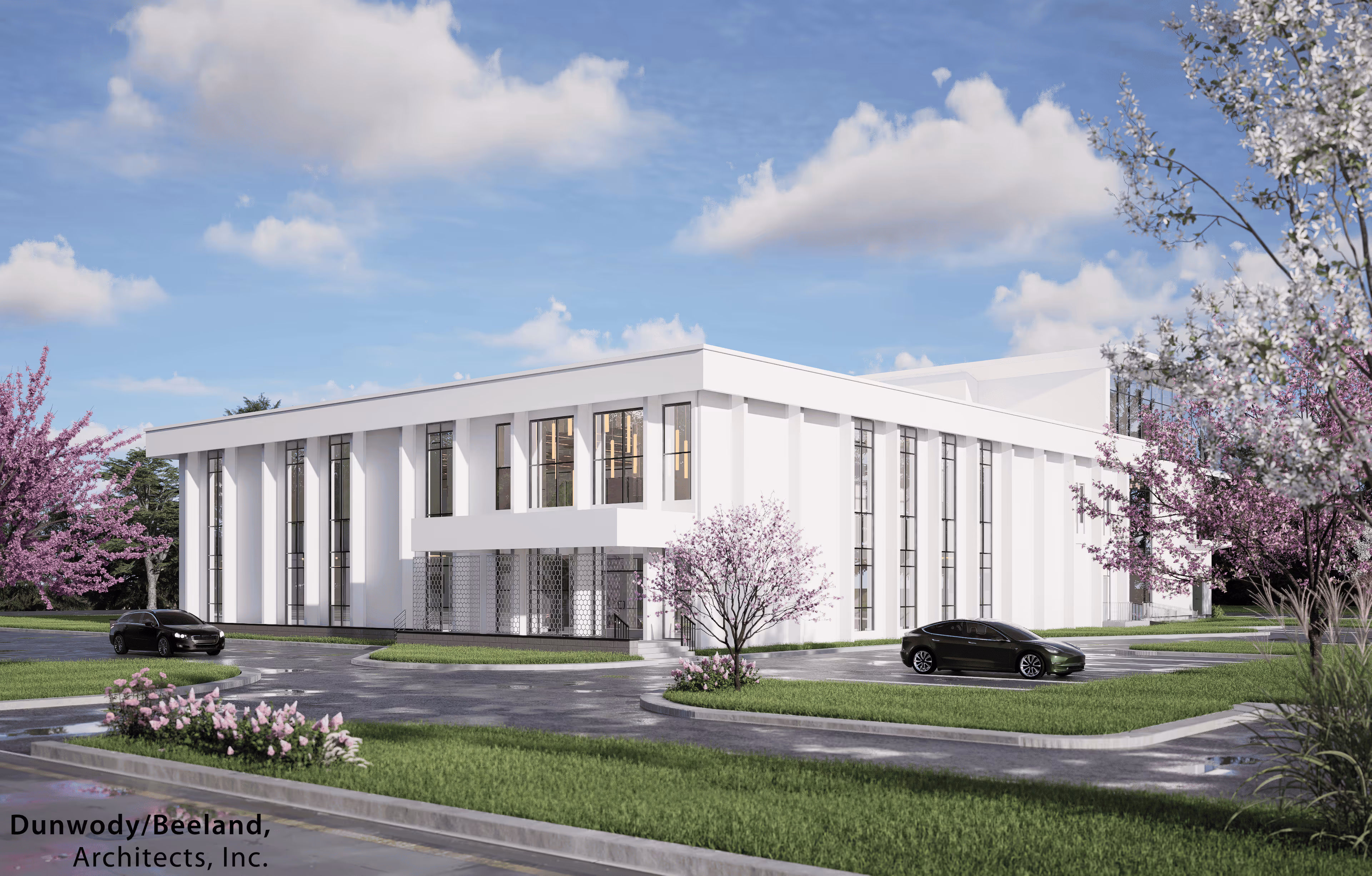 Modern two-story white office building with large vertical windows, surrounded by green grass, flowering trees, and two black cars in the parking lot under a partly cloudy blue sky.