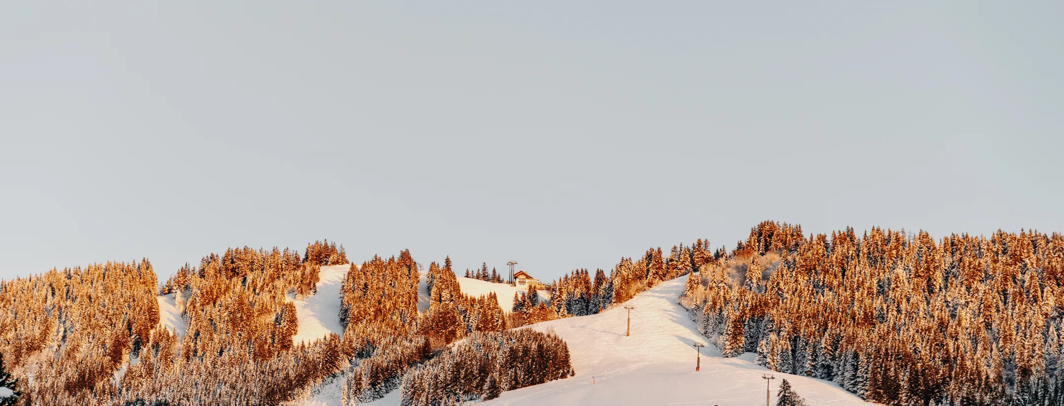 Panoramic view of the snowy mountains and chalets in Megève at sunrise.