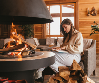 Femme lisant au coin du feu au Refuge du Mont d’Arbois, ambiance chaleureuse et alpine.