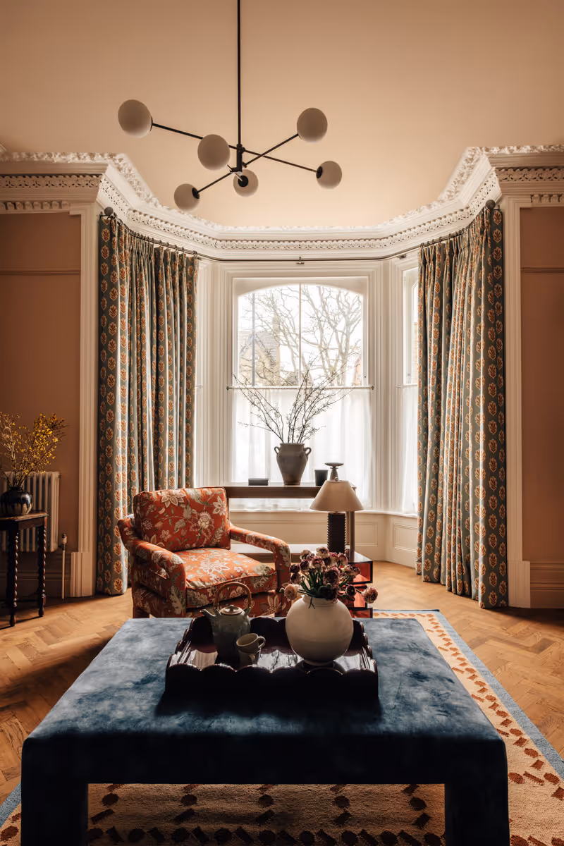 Preview of the Ross Road project with a pink wardrobe  beside a white table holding potted plants, children's books, and rolled colouring sheets against floral wallpaper.