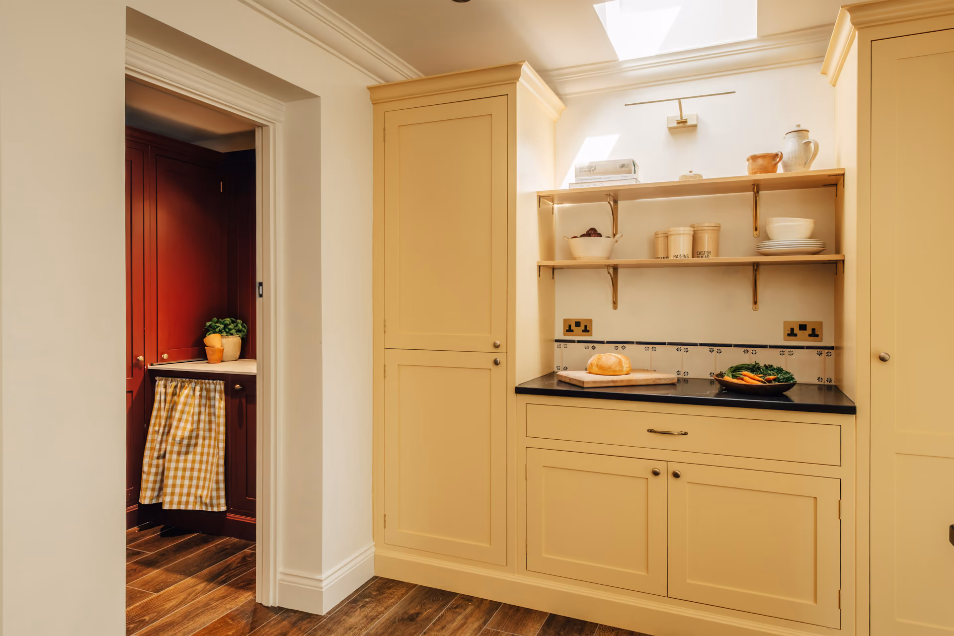 Modern kitchen with wooden island, stools, black refrigerator, dining table with wooden chairs, and vase of orange flowers.