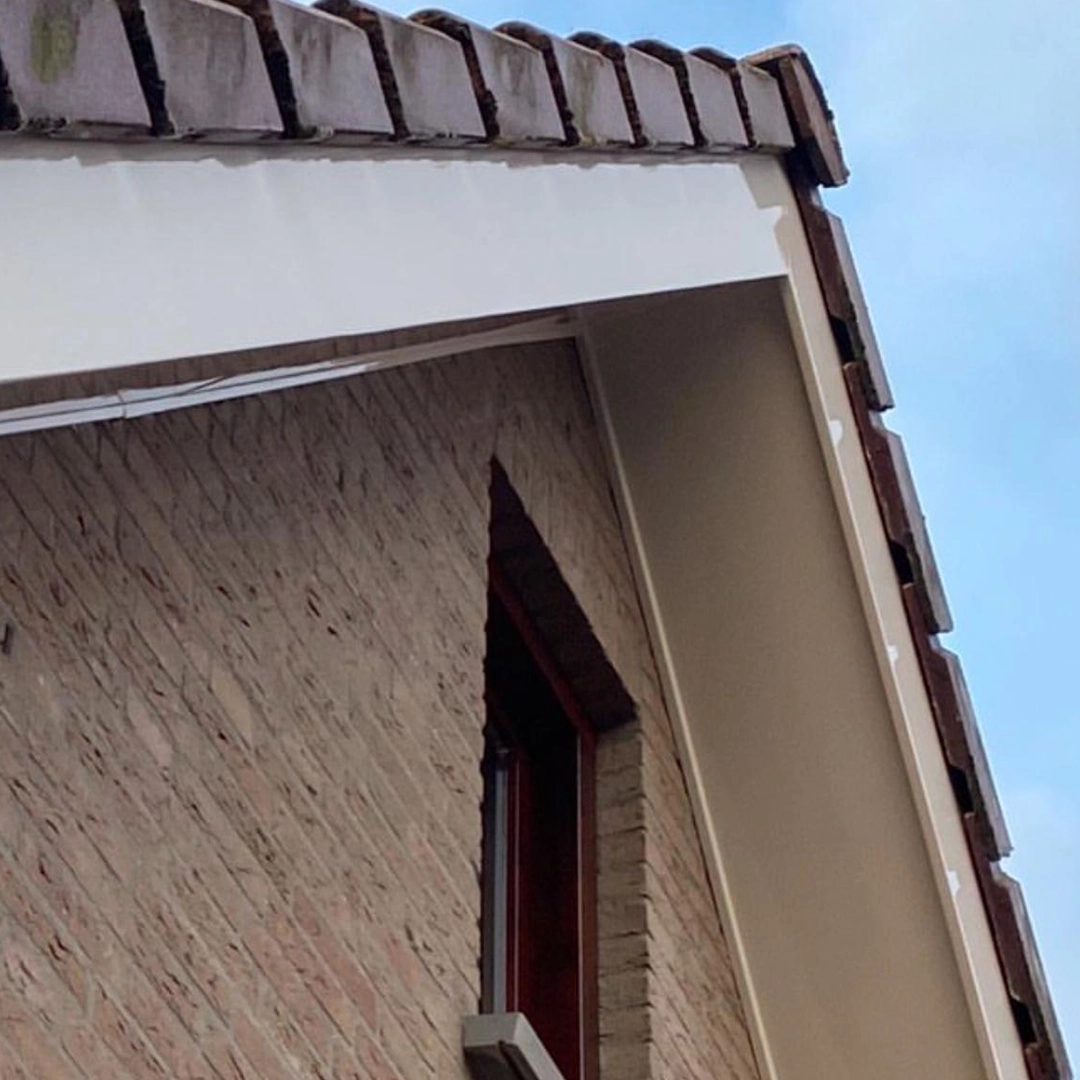 Buitenzijde van een woning met net geschilderde witte dakrand en bakstenen gevel.