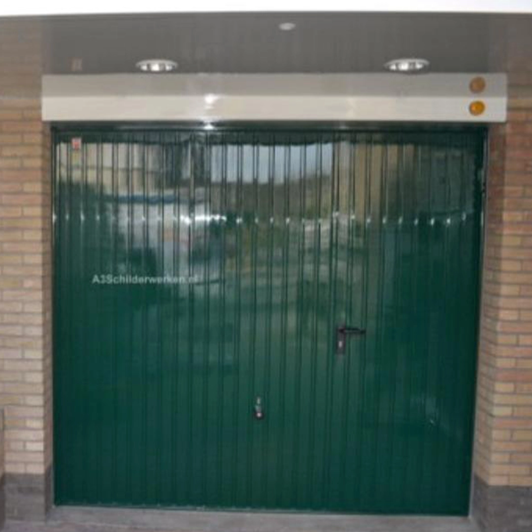 Donkergroen gelakte garagedeur tussen twee bakstenen muren, glanzend afgewerkt.