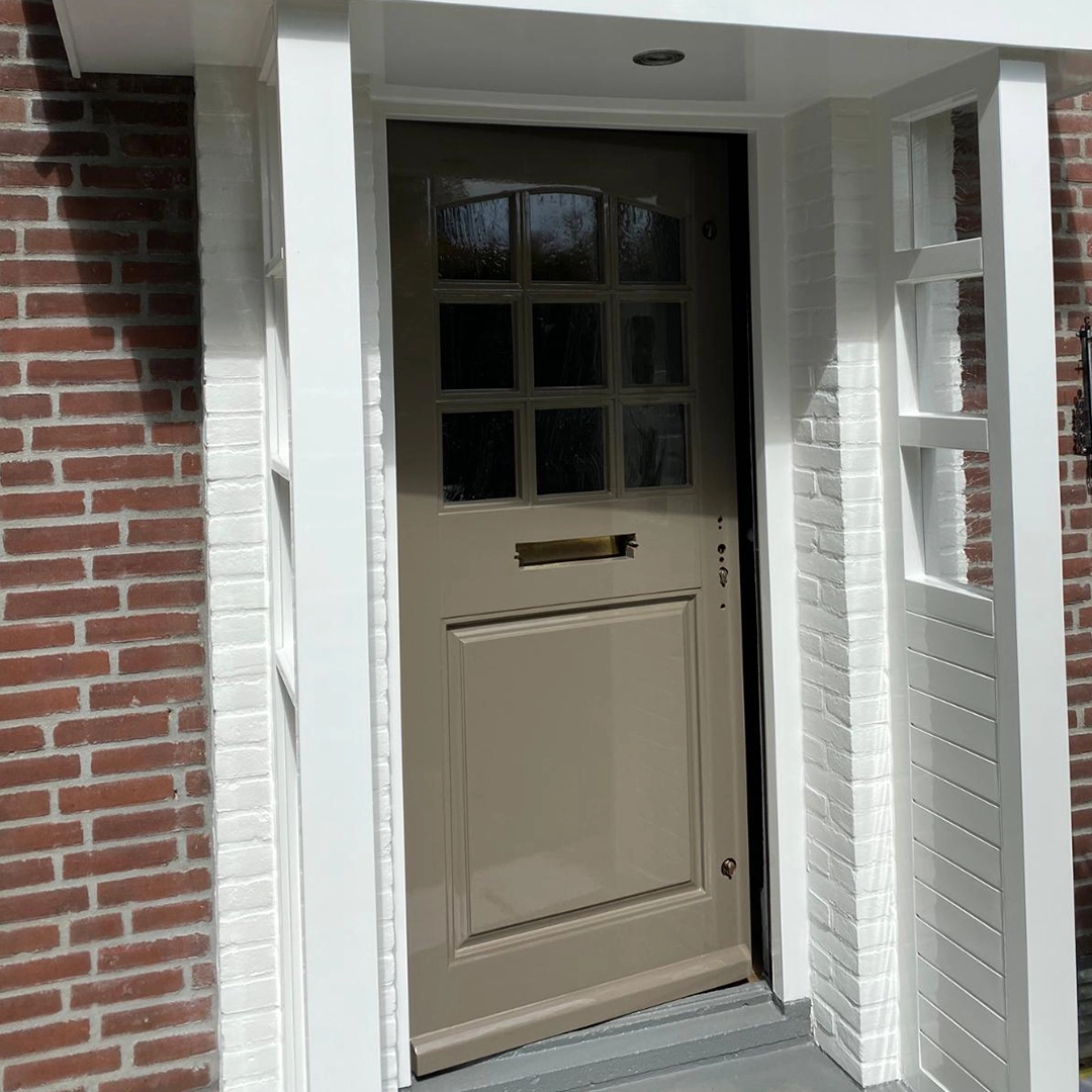 Vers geschilderde bruingrijze voordeur met glazen ruitjes en glanzende laklaag.