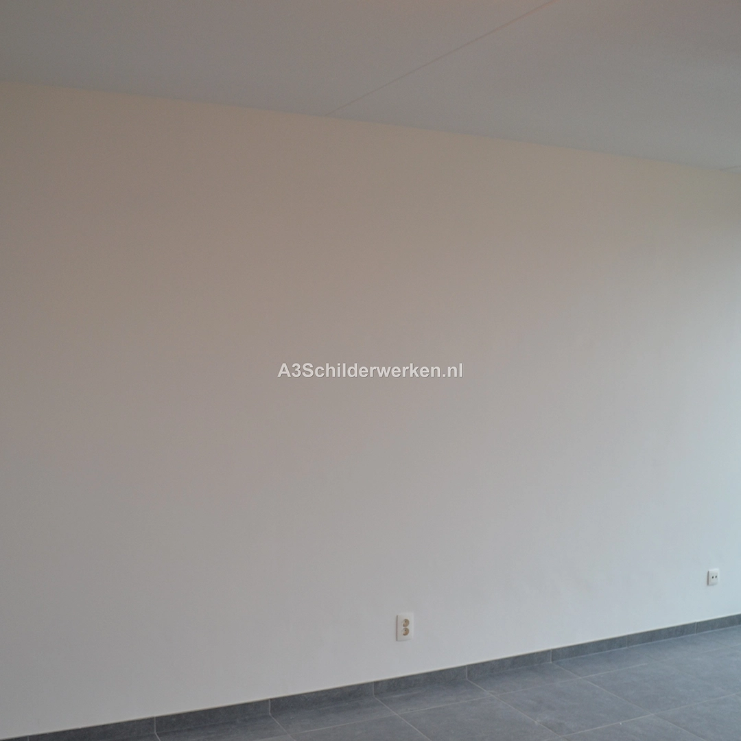 Strak afgewerkte en egaal wit gesausde muur na wandafwerking.