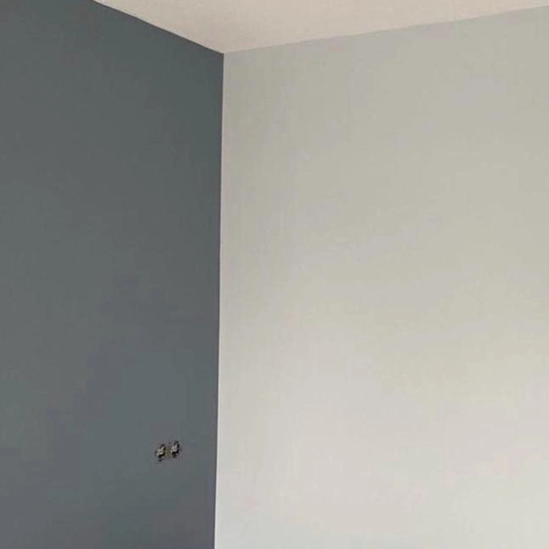Strak geschilderde hoekwand met een stijlvolle combinatie van wit en diepblauwgrijs voor een modern en rustig contrast.