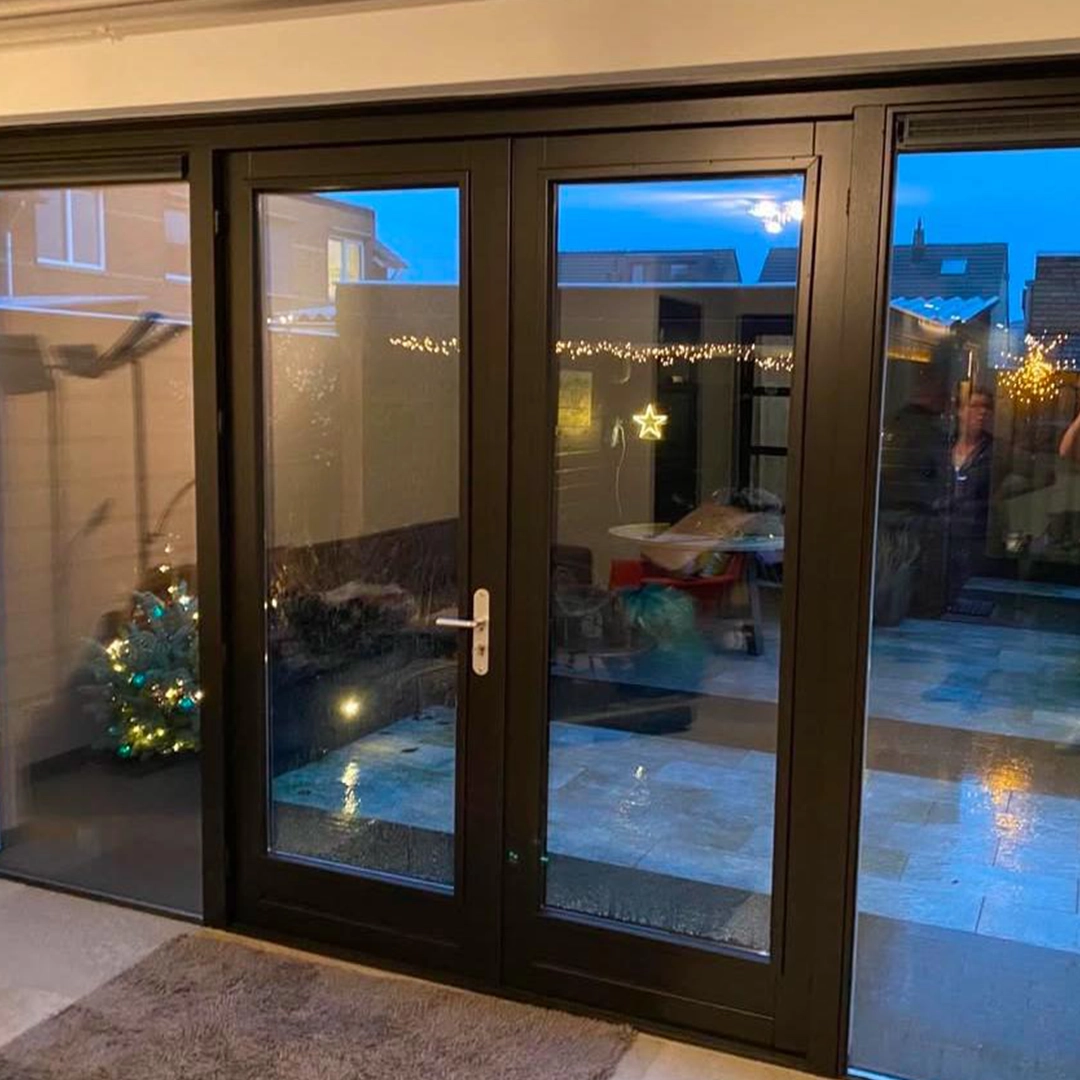 Strak afgewerkte zwarte kozijnen en deuren geven deze ruimte een luxe en moderne uitstraling. In combinatie met de warme binnenverlichting en sfeervolle decoratie ontstaat een gezellige, uitnodigende sfeer.