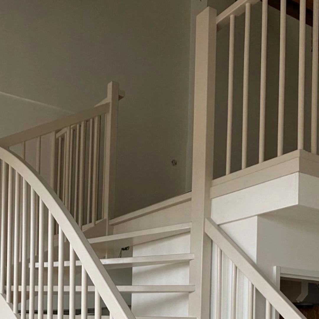 Deze trap is prachtig in een lichte, zachte kleur afgewerkt, wat zorgt voor een rustige en open uitstraling in de ruimte. De ronde lijnen in de leuning geven een speels contrast met het strakke, rechte lijnenspel van de spijlen en treden. Perfect uitgevoerd en ideaal voor een modern maar warm interieur.