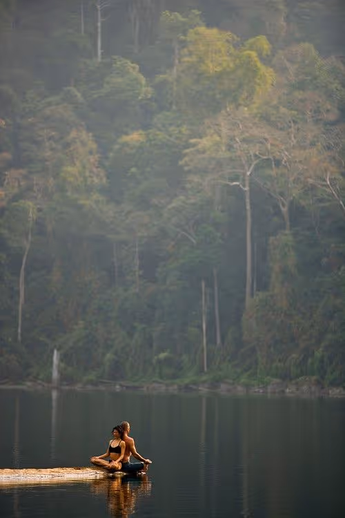 Deux personnes pratiquant le yoga ensemble au bord d'un lac.