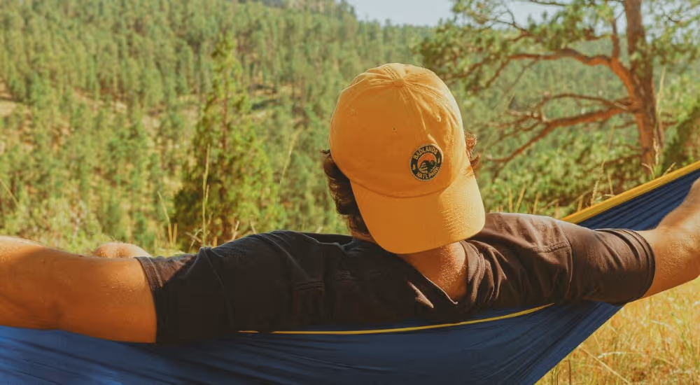 Homme allongé dans un hamac face à un piton rocheux.