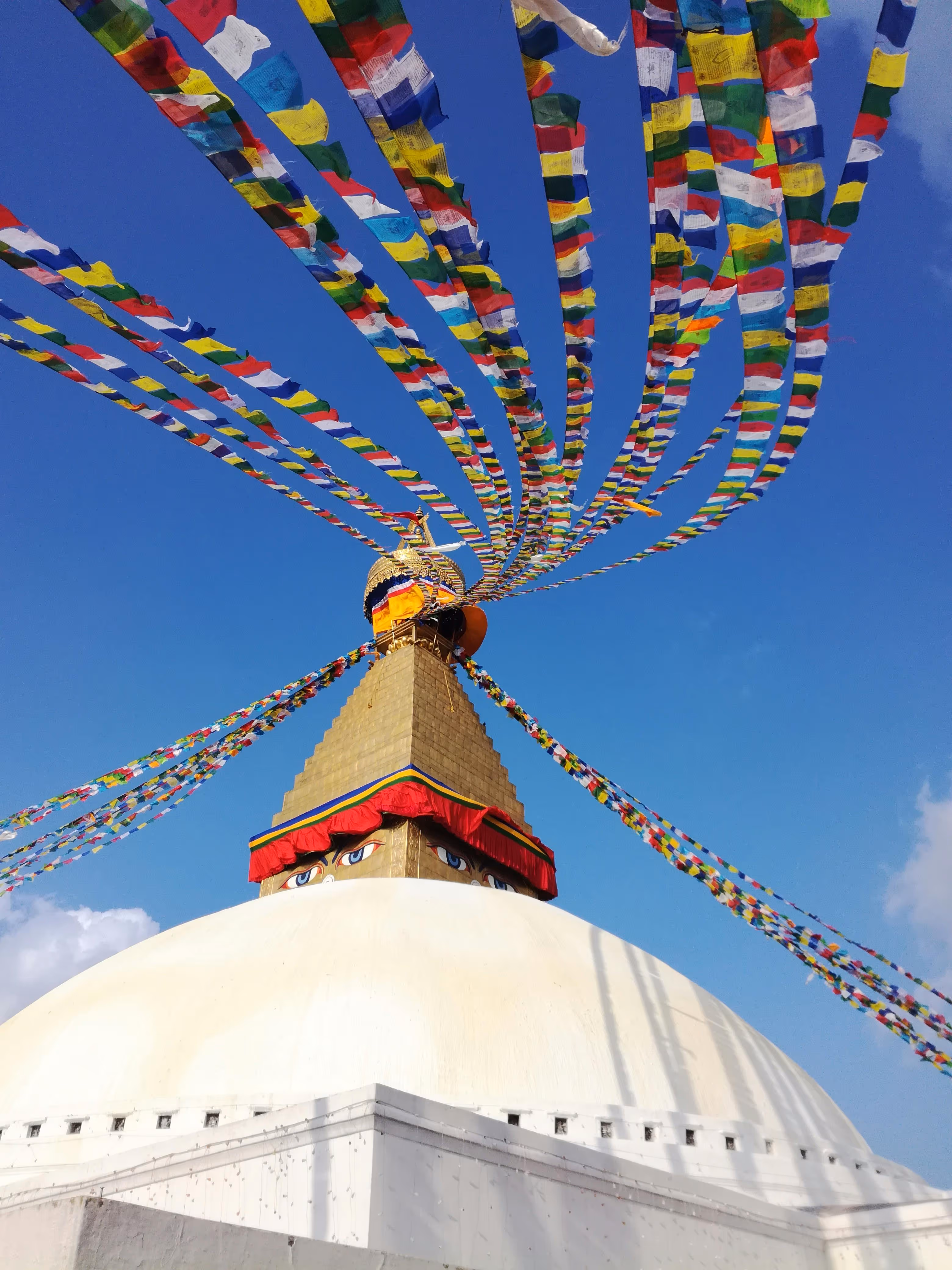 Grand stupa blanc avec drapeaux de prières flottants.