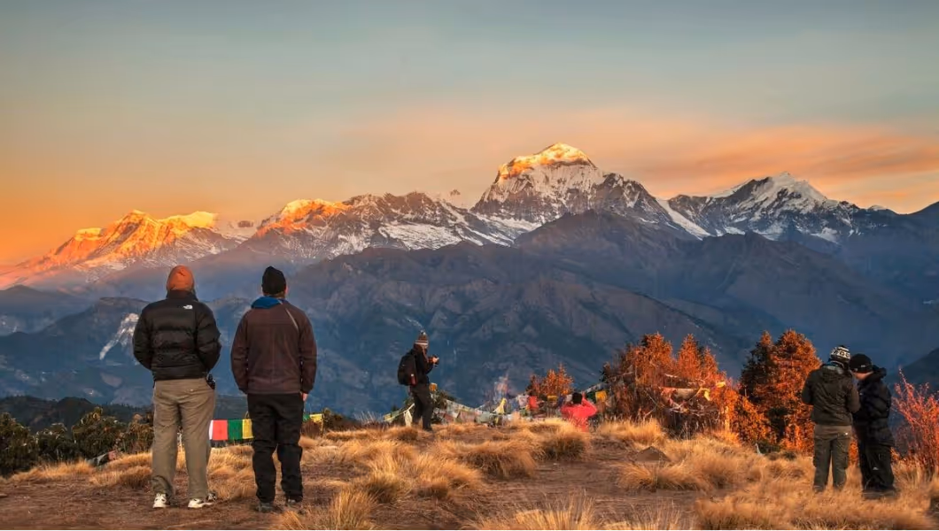 Groupe de randonneurs observant un lever de soleil sur les montagnes.