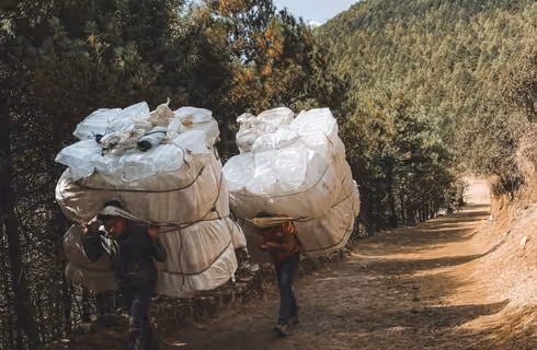 Porteurs népalais transportant de lourdes charges sur un sentier de montagne.